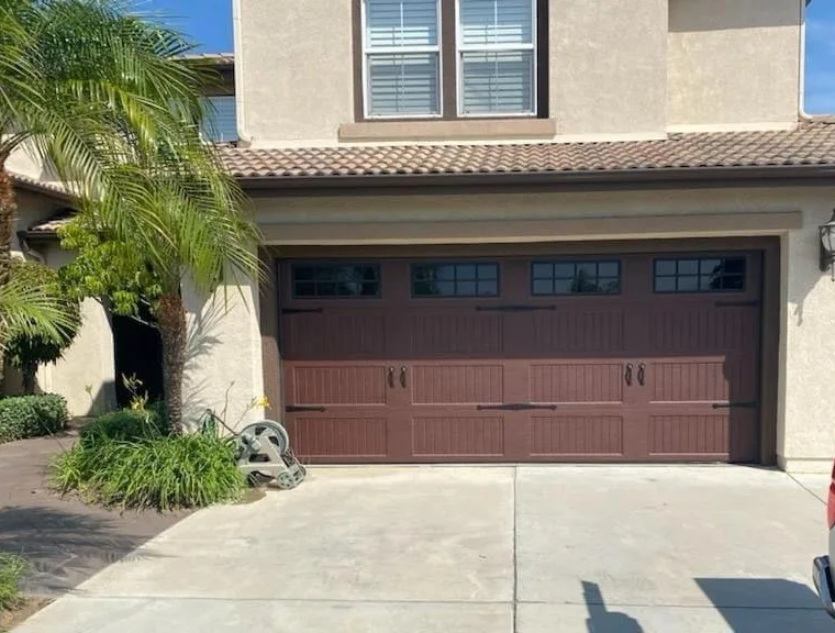 Brown carriage-house garage door with top windows and black handles
