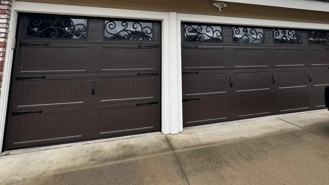 Pair of brown carriage-house garage doors with wrought-iron window inserts on a two-car garage